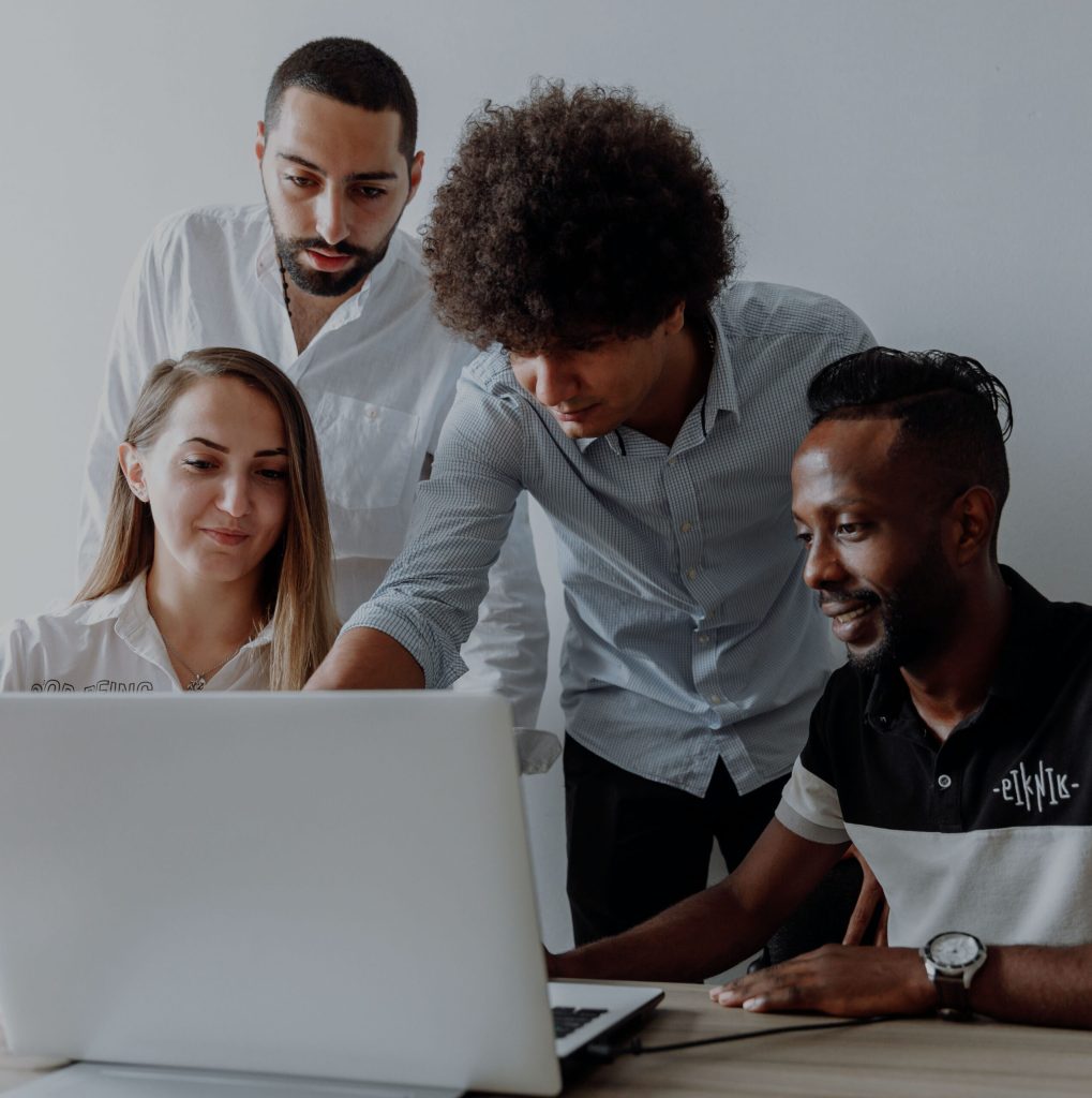 This is a photo of a team in a meeting room referring to a computer monitor doing a workshop with Dr. Liz Wilson from Include Inc. - Diversity and inclusion expert consultant