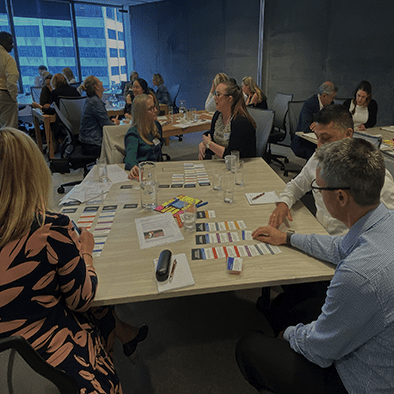 This is a photo of a workshop being facilitated by Dr. Liz Wilson from Include Inc. - Diversity and inclusion expert consultant. Participants are sitting a workshop tables working with inclusion toolkit cards.
